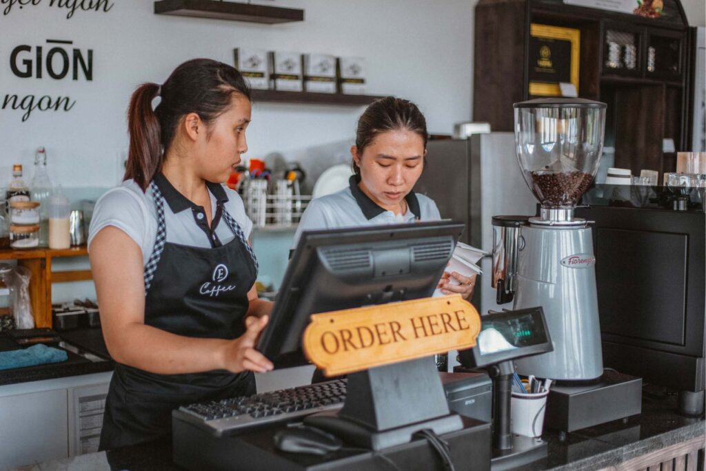 two workers behind the register at a coffee shop