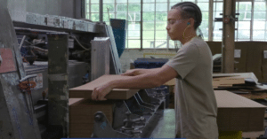 young man working at a machine folding boxes